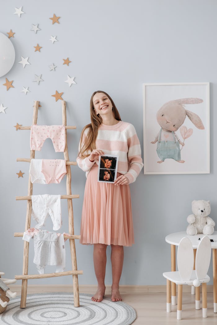 A joyful pregnant woman displaying an ultrasound in a beautifully decorated nursery.