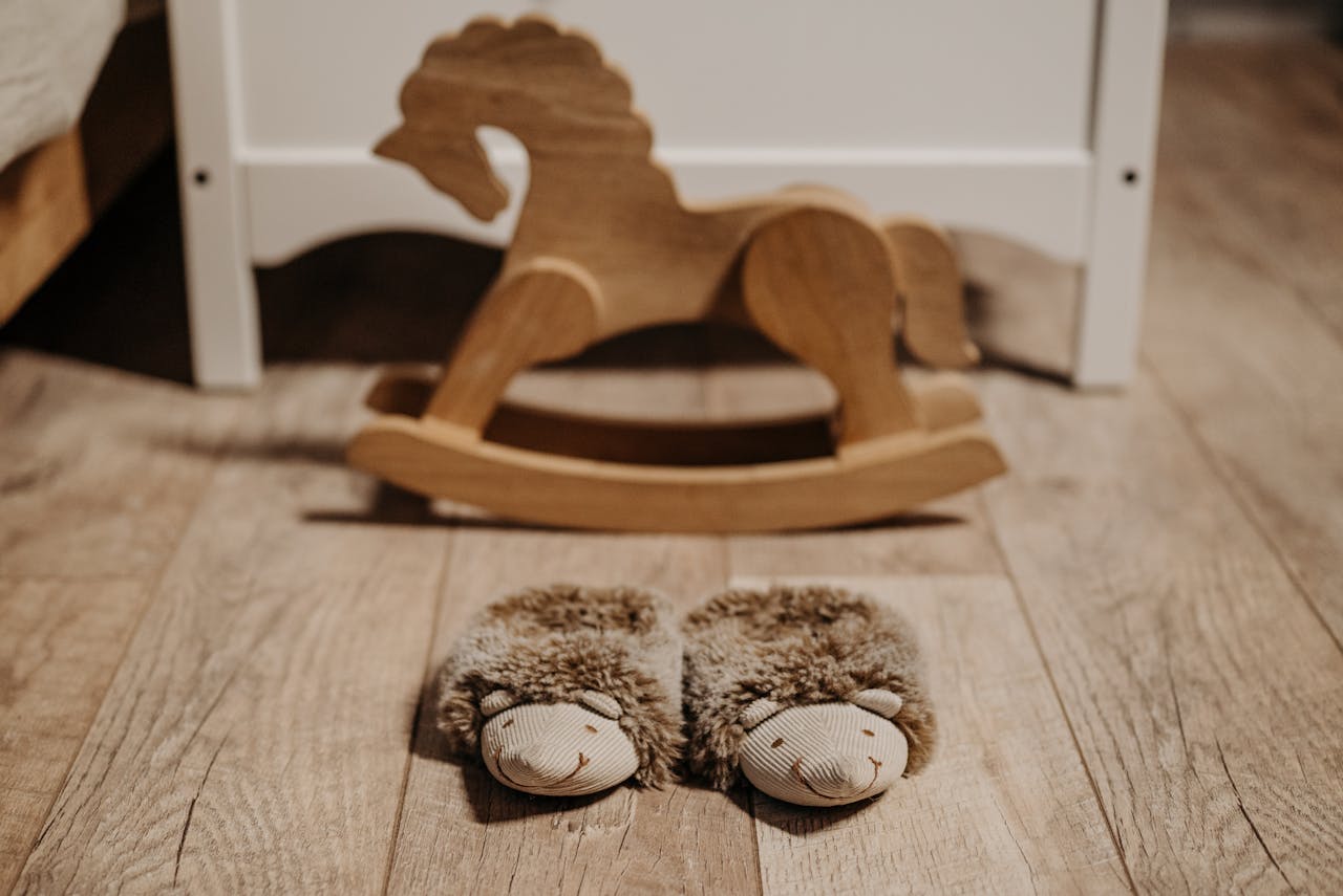 about-img Warm, fluffy slippers on wooden floor in nursery beside a wooden rocking horse.
